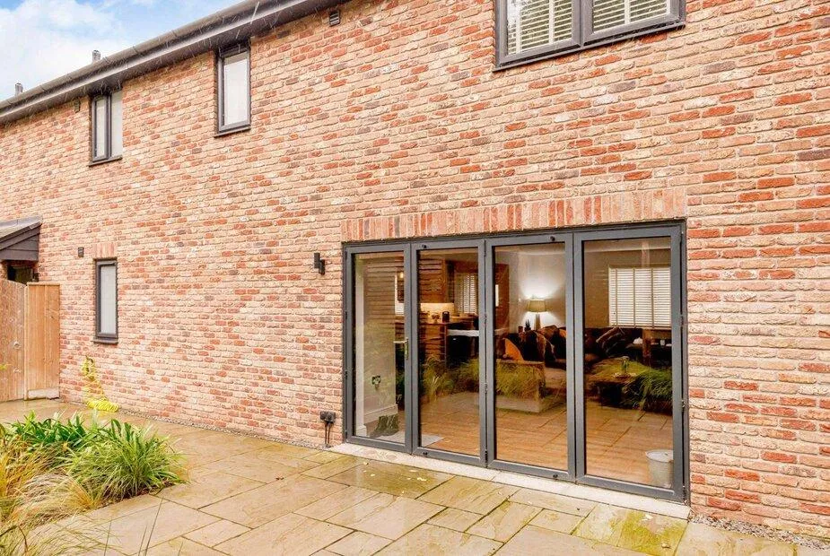 Brick exterior of cottage with large patio doors leading to garden area
