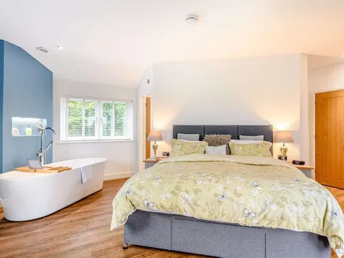 Cottage bedroom with double bed and freestanding bathtub by window