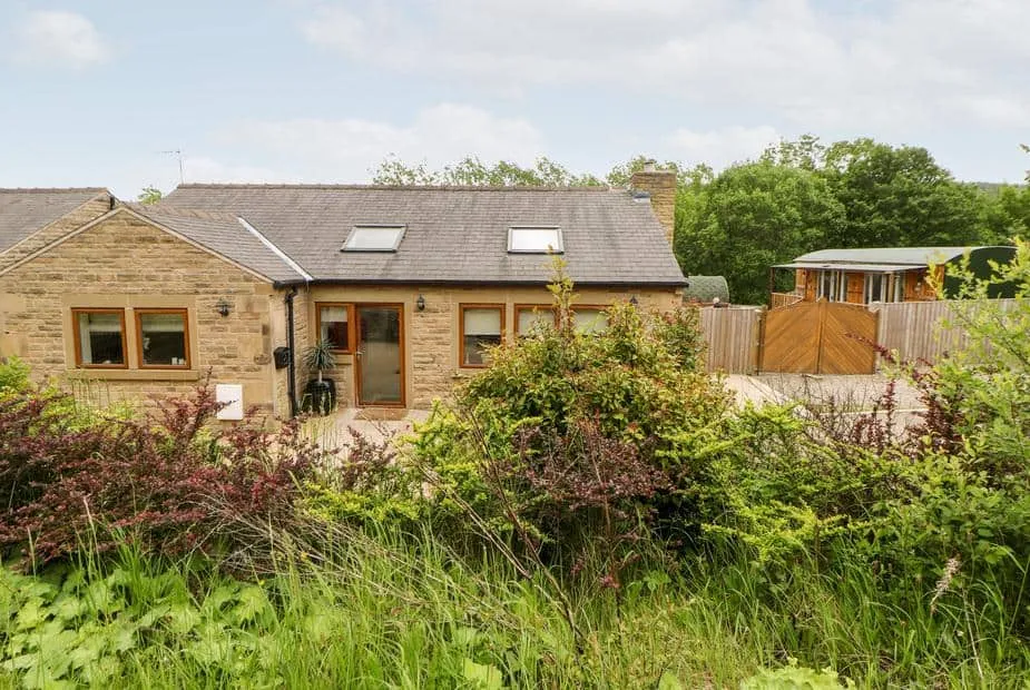 2 Pheasant Lane stone cottage with skylights and garden shrubs in the foreground