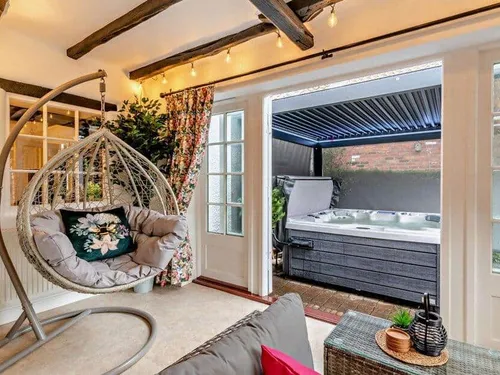 Lounge with hanging chair and doors opening to covered hot tub area