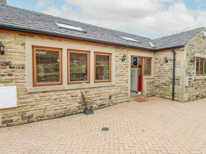 4 Pheasant Lane stone-fronted bungalow with skylights, wooden-framed windows, and red front door on a block-paved drive