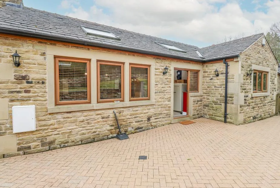 4 Pheasant Lane stone-fronted bungalow with skylights, wooden-framed windows, and red front door on a block-paved drive