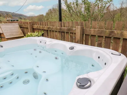 Hot tub in the front garden with wooden fencing and countryside views toward the Peak District hills