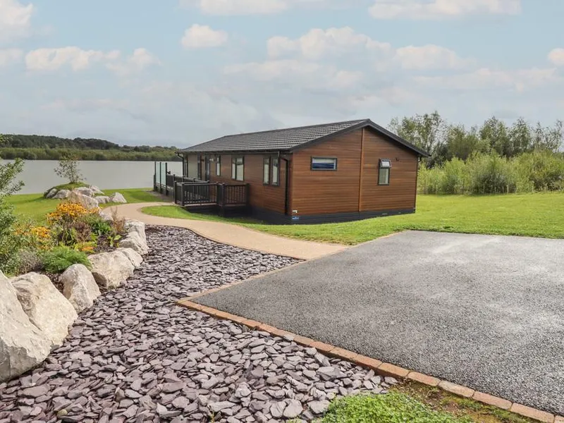 Lodge with decking overlooking a lake and landscaped garden