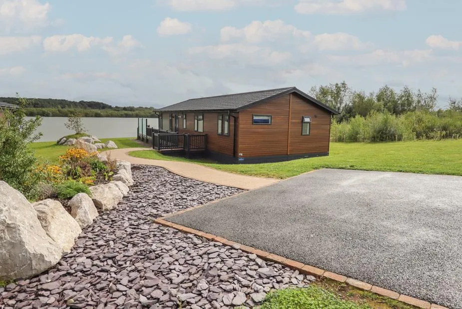 Lodge with decking overlooking a lake and landscaped garden