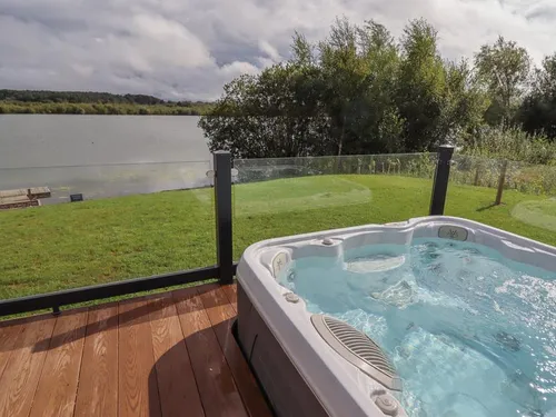 Lodge decking with hot tub overlooking lake and grassy area