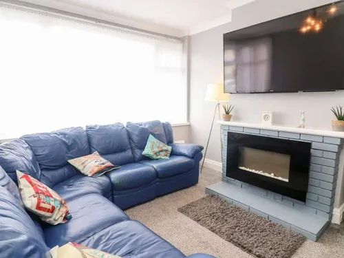 Cottage living room with blue corner sofa and wall-mounted television above fireplace