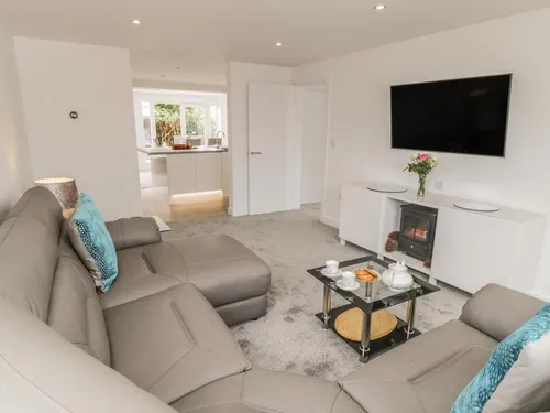 Open-plan lounge with grey leather corner sofa and wall-mounted TV
