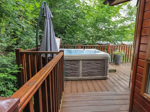 Lodge decking with hot tub and outdoor umbrella by wooden railing