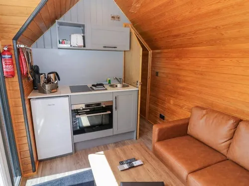 Lodge interior with compact kitchen area and brown leather sofa