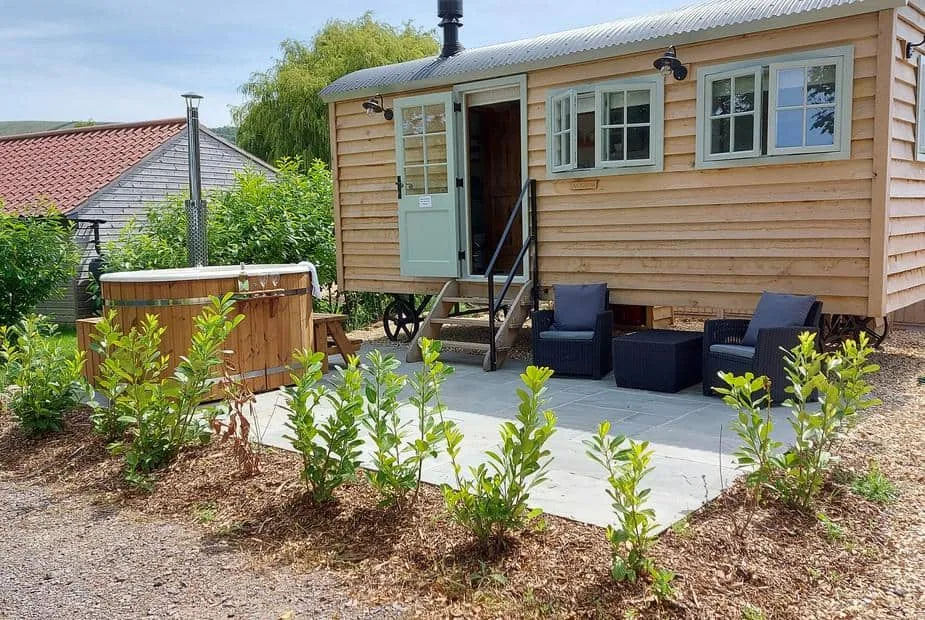 Acorn cottage exterior with seating area and wooden hot tub on patio