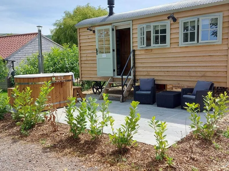 Acorn cottage exterior with seating area and wooden hot tub on patio