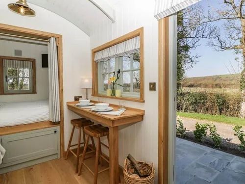 Cottage kitchen with breakfast bar, stools and open door to garden view