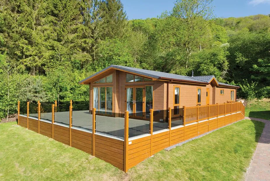 Ashton Elegance Premier lodge with glass-panelled decking and wooded Mendip hillside behind