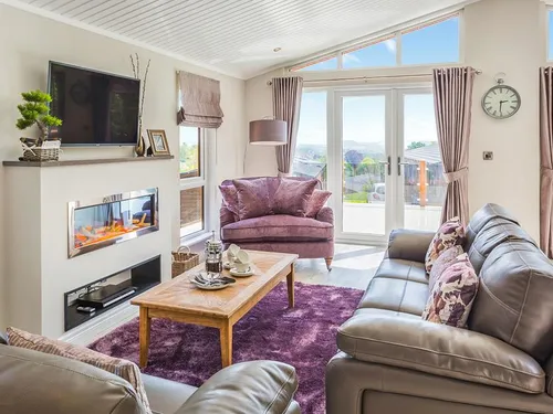 Living room with modern fireplace, leather sofas, purple armchair, and patio doors to the deck