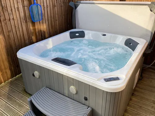 Hot tub with grey panelling on enclosed timber decking with step access