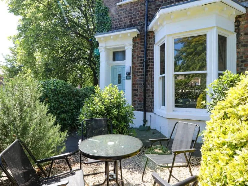 Baggergate House front garden with glass table and chairs surrounded by greenery