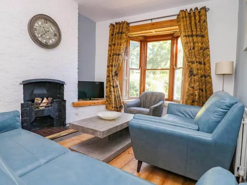 Living room with blue sofas, bay window and wood-burning stove