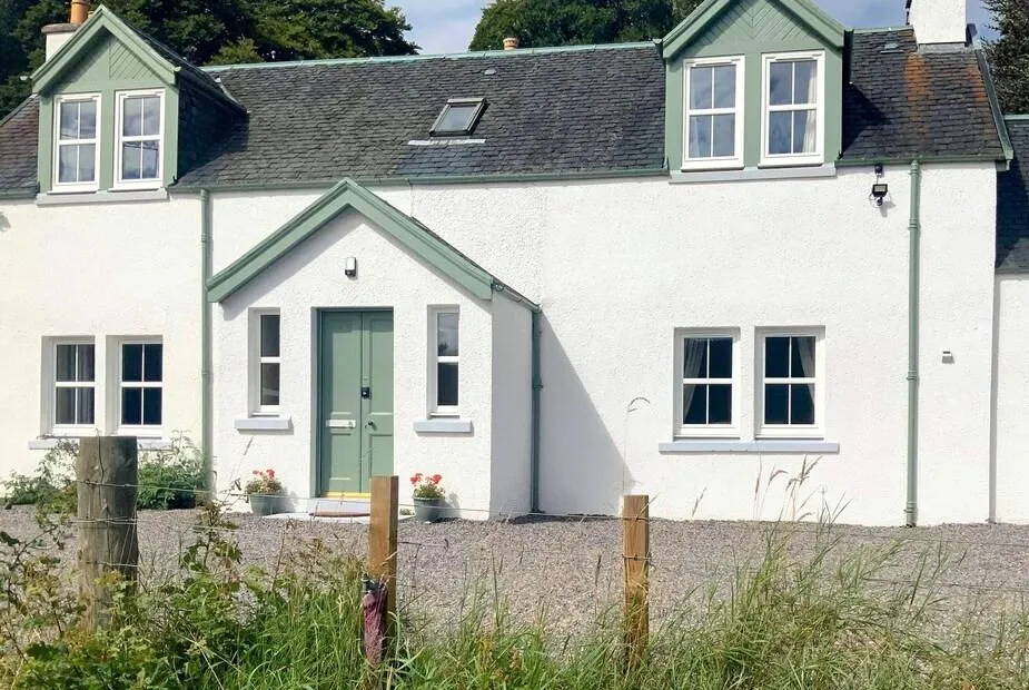 White-rendered Highland farmhouse with sage green front door and dormer windows