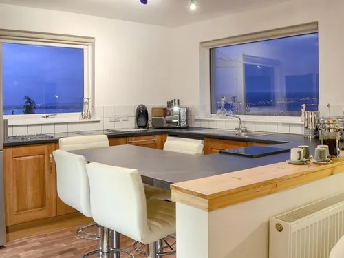 Kitchen with oak cabinets, breakfast bar, and evening views across the water through large windows