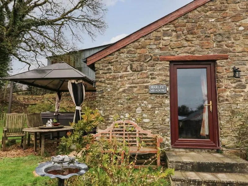 Stone exterior of Barley Meadow with garden seating area and gazebo.