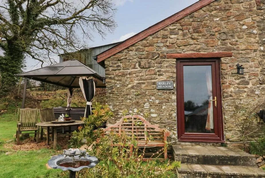 Stone exterior of Barley Meadow with garden seating area and gazebo.