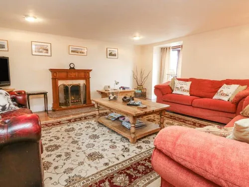 Cottage living room with red sofas, fireplace and wooden coffee table