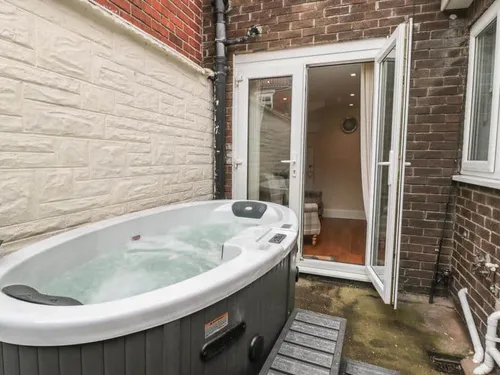 Cottage patio with hot tub next to open French doors