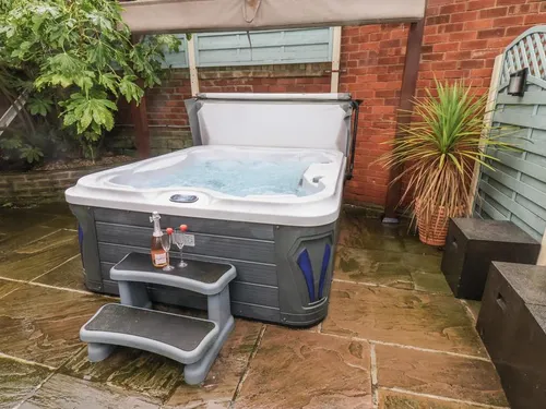 Hot tub on flagstone patio in sheltered rear courtyard with brick walls and parasol overhead