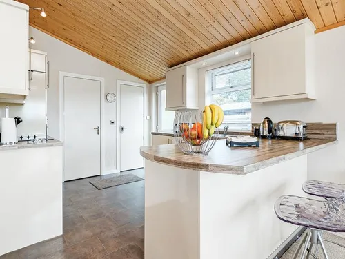 Kitchen with breakfast bar, wooden worktops, bar stools, and pine-clad ceiling