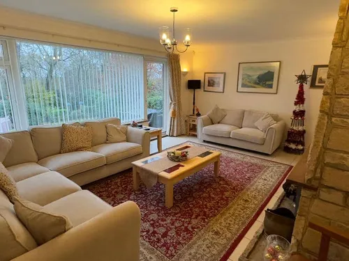 Cottage living room with cream sofas, coffee table and large window overlooking garden