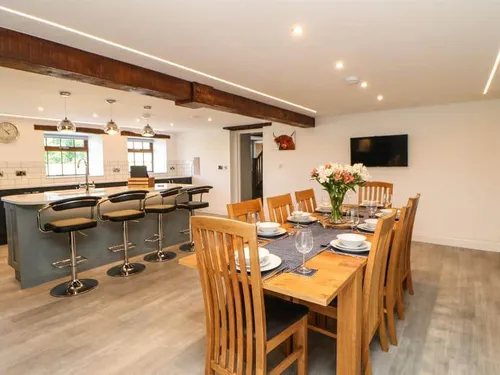Cottage kitchen and dining area with wooden table and breakfast bar with stools