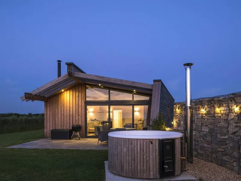 Lodge with outdoor hot tub and stone feature wall at dusk