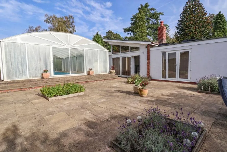 Bramble Lodge with paved patio and enclosed swimming pool visible in the garden.
