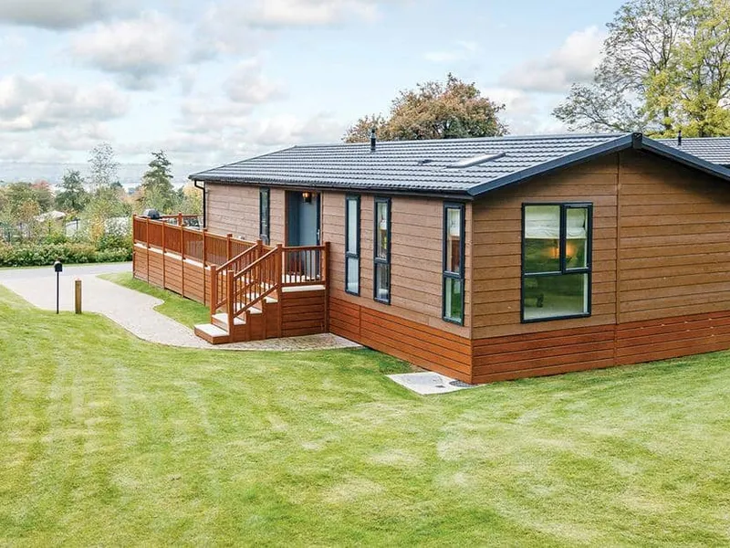 Lodge with decking surrounded by grass and trees