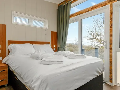 Lodge bedroom with double bed and sliding glass doors to balcony