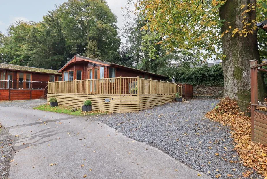 Buttermere Lodge with decked veranda beside a large tree and gravel driveway