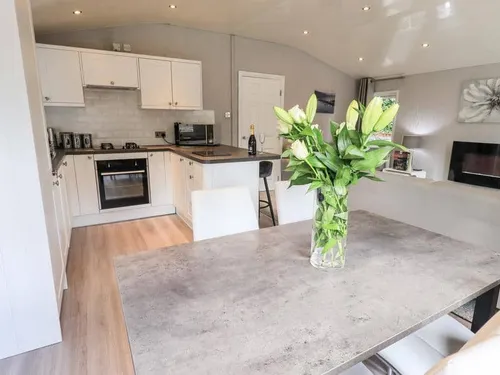 Lodge kitchen and dining area with table, vase of flowers and integrated appliances