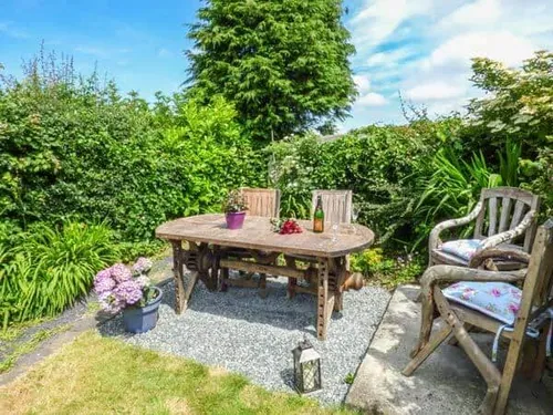 Cottage garden patio with wooden table and chairs