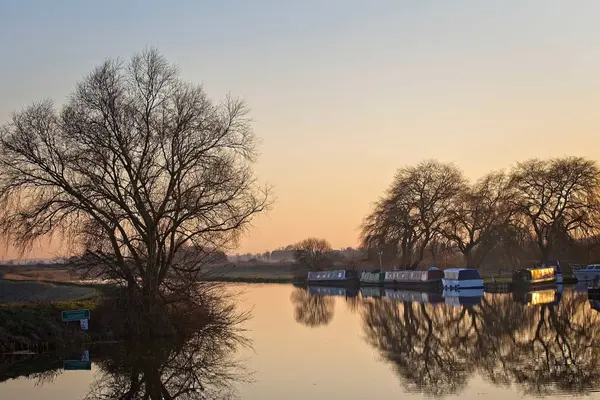 Sunset reflecting on the calm waters of the River Cam in the Cambridgeshire Fens.