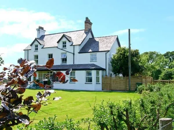 Carreg Rhys cottage with large lawn and surrounding garden shrubs
