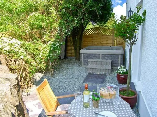 Cottage patio with dining table and hot tub in garden area