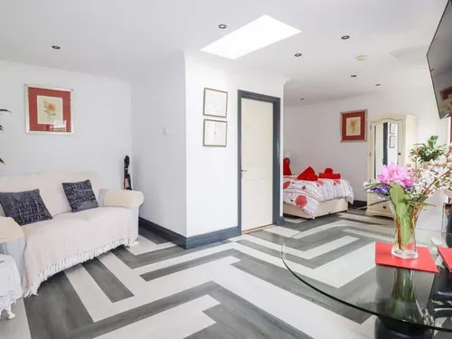 Cottage lounge with sofa, dining table and view into bedroom with double bed