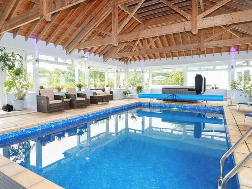 Cottage indoor pool with wicker seating and wooden beamed ceiling
