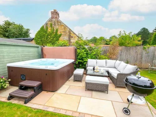 Cottage patio with hot tub, rattan seating and charcoal barbecue grill