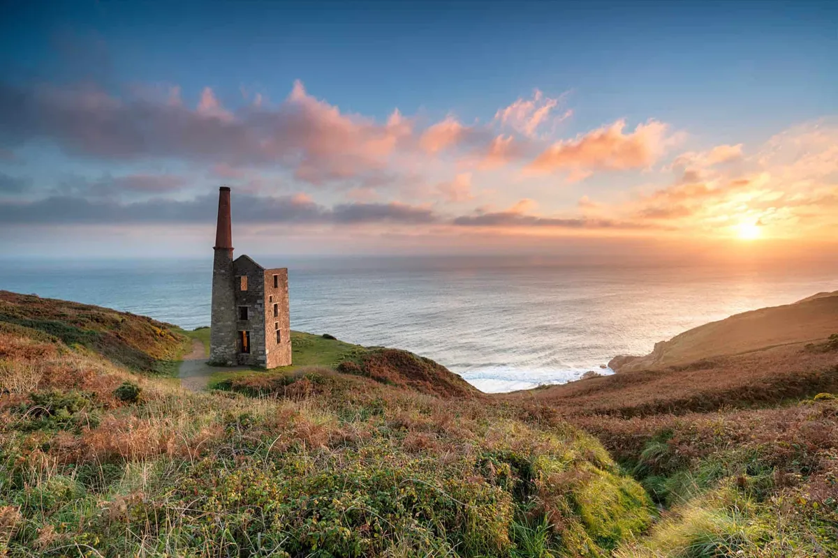 Golden sunset over the historic Rinsey Head engine house in Cornwall, sitting on a cliff edge overlooking the Atlantic Ocean