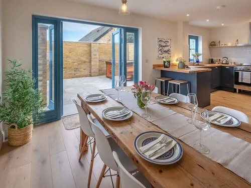 Cottage dining area with set table and view into kitchen and patio through open doors