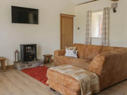 Living room with brown sofa, electric stove, and wall-mounted TV