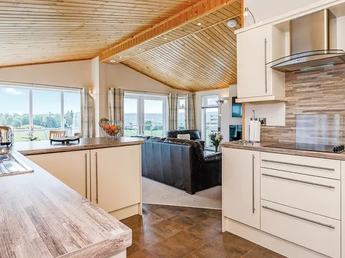 Open-plan kitchen and living area with vaulted pine ceiling and countryside views through large windows