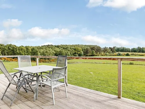 Decking with metal garden furniture and wide views across green meadowland and woodland